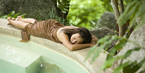 Woman having a nap next to a swimming pool